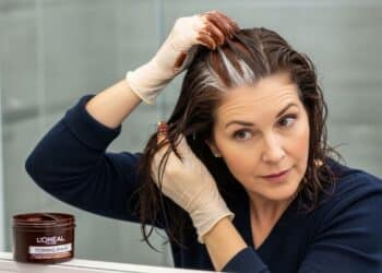 Caixa de tinta Koleston sem amônia posicionada sobre bancada de banheiro organizada, ao lado mecha de cabelo com fios brancos visivelmente cobertos e brilho uniforme, representando cobertura de até 80% com saúde capilar preservada