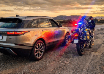 SUV de luxo prateado parado no acostamento por uma moto da polícia com giroflex ligado