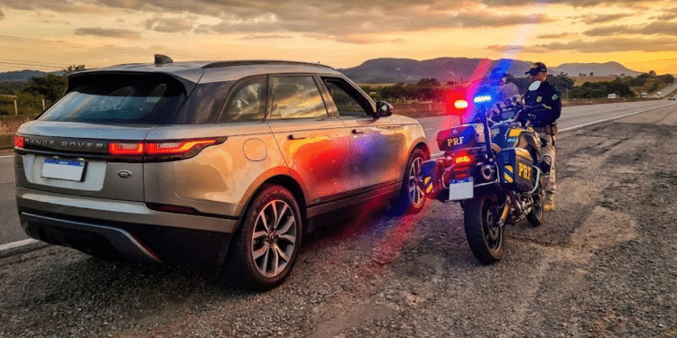 SUV de luxo prateado parado no acostamento por uma moto da polícia com giroflex ligado