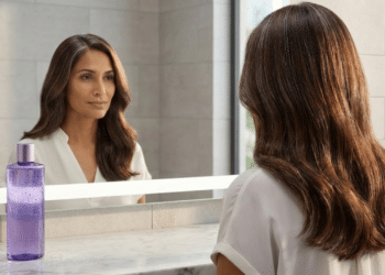 Mulher admirando cabelo com brilho e camuflagem natural no espelho