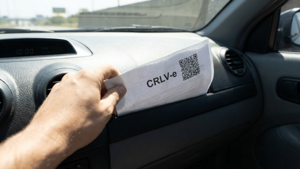 Mão do motorista pegando a versão impressa do CRLV-e no porta-luvas