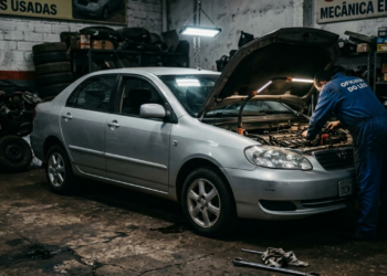 Carro com capô aberto em oficina com iluminação dramática e tensa
