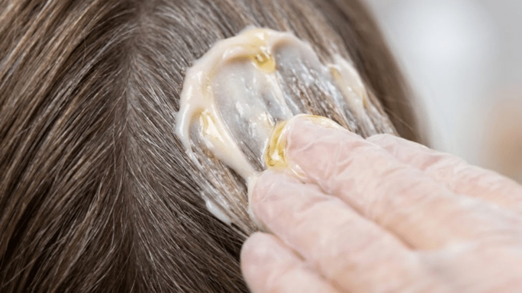 Macro da textura cremosa da coloração sem amônia sendo aplicada no cabelo