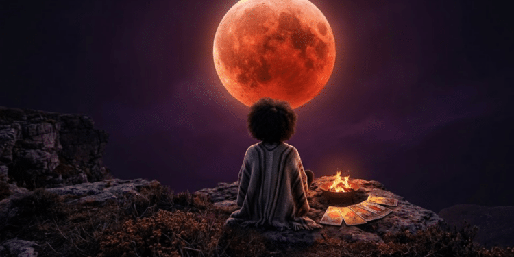 Uma pessoa de costas em um penhasco rochoso, observando a imponente Lua de Sangue no céu noturno ao lado de uma fogueira e cartas de tarô.