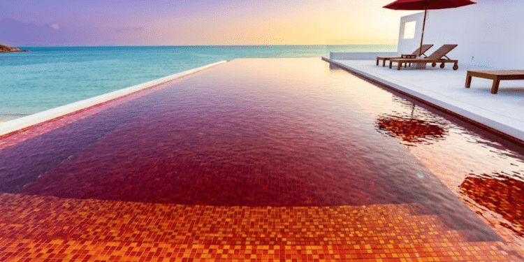 Piscina rubi contrasta com mar azul ao pôr do sol