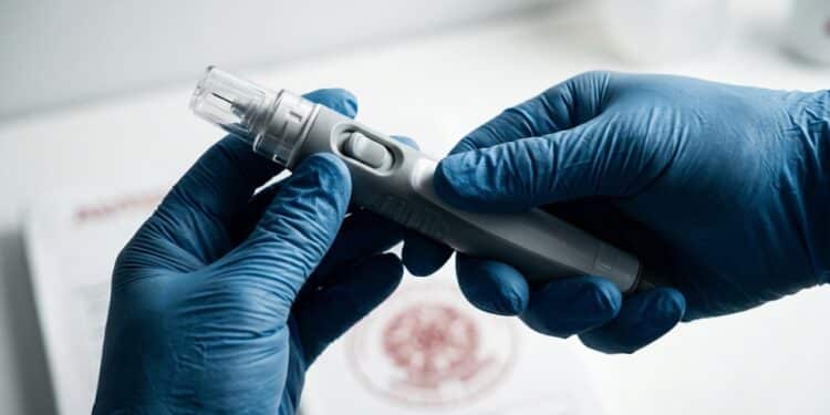 Mãos com luvas segurando autoinjetor sob iluminação dramática