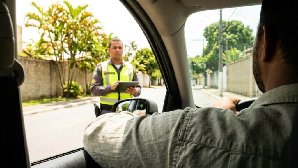 Visão sobre o ombro de motorista observando agente de trânsito em fiscalização, simbolizando o cumprimento das normas