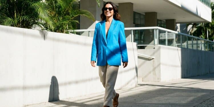 Mulher usando blazer oversized azul em uma rua ensolarada