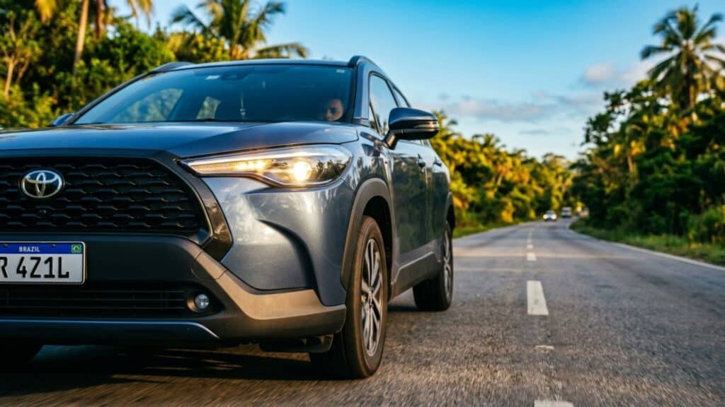 Farol de carro moderno aceso em rodovia sob sol forte