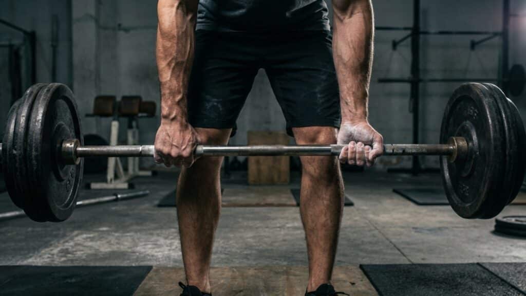 Detalhe de mãos com magnésio segurando barra em pausa estática