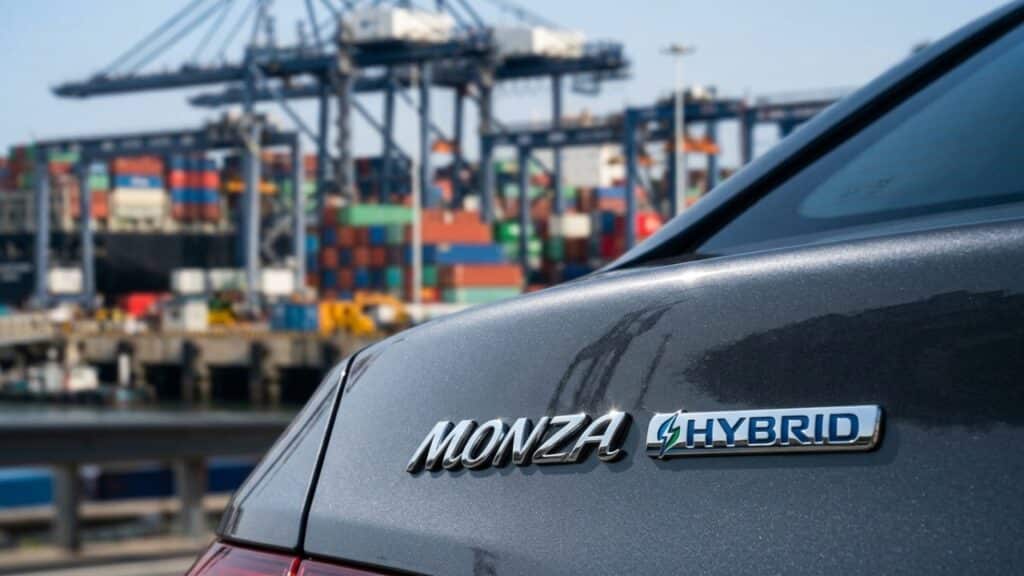 Detalhe do emblema híbrido do Monza com porto de exportação ao fundo
