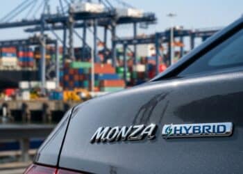 Detalhe do emblema híbrido do Monza com porto de exportação ao fundo