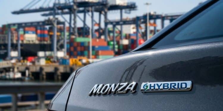 Detalhe do emblema híbrido do Monza com porto de exportação ao fundo